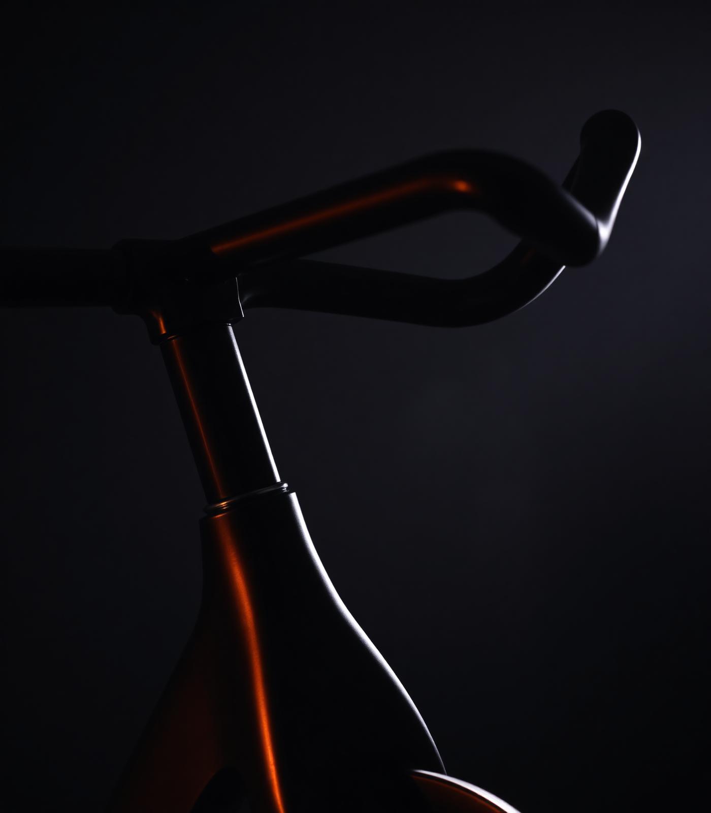 Close-up of a matte black spin bike lit by warm ember light
